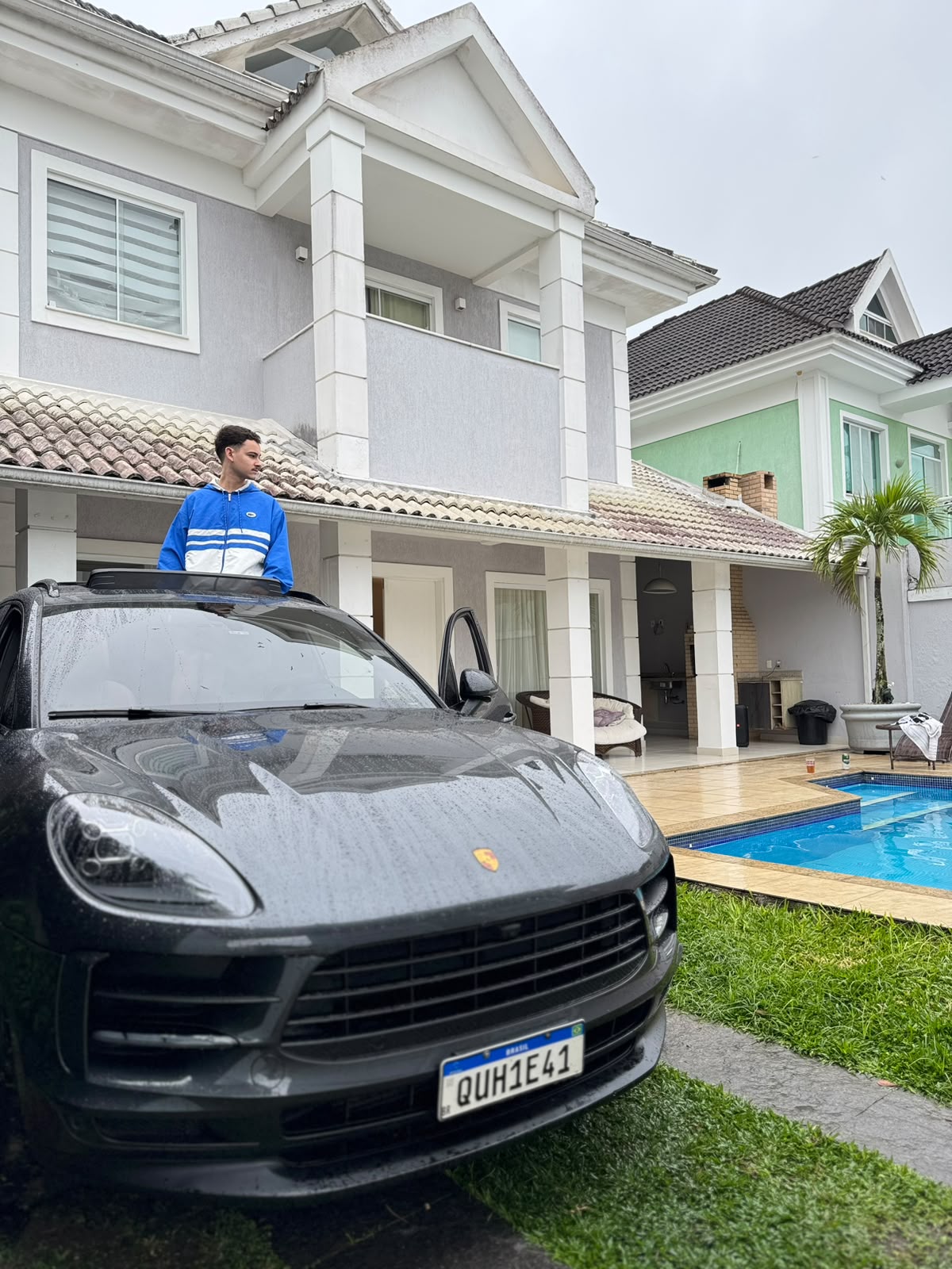 Davi Couto em frente a uma casa, ao lado de um carro